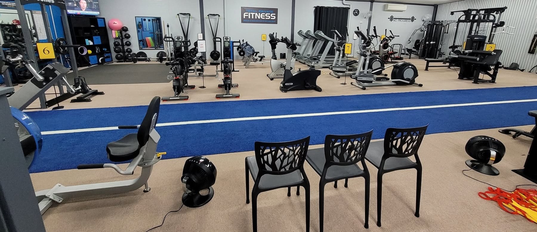 The Total Private Fitness training floor in Grafton, with cardio machines, racks and the blue turf lane running down the centre